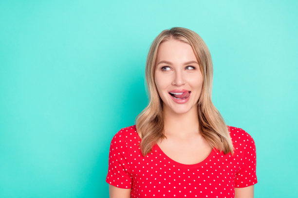 照片肖像，金发女子舔嘴唇，看向空白处，穿着红点T恤，背景是鲜艳的青色图片下载