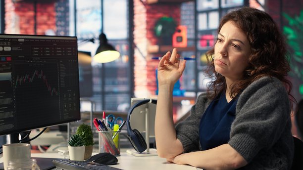 专注的女性在电脑前研究股票交易图表图片下载