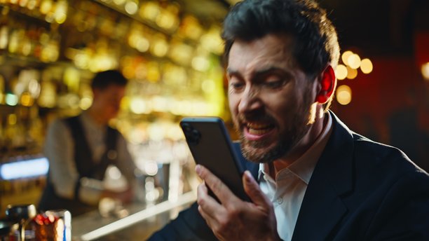 夜晚酒吧近景，紧张的男人在打电话争吵。愤怒的男人在吼叫。图片下载