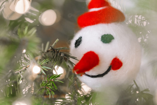 云杉枝上的雪人头圣诞树装饰挂件，饰有彩灯。圣诞和新年装饰。美丽的圣诞节日背景。雪人挂件特写在圣诞树上。图片下载