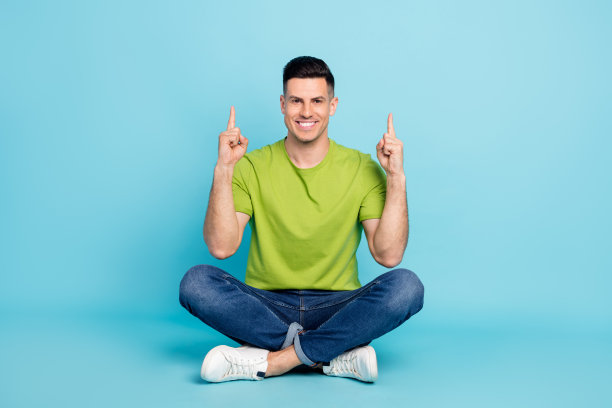 身穿休闲装的快乐年轻男子，正面朝上，对准空白处微笑，孤立在蓝色背景上，全尺寸照片图片下载