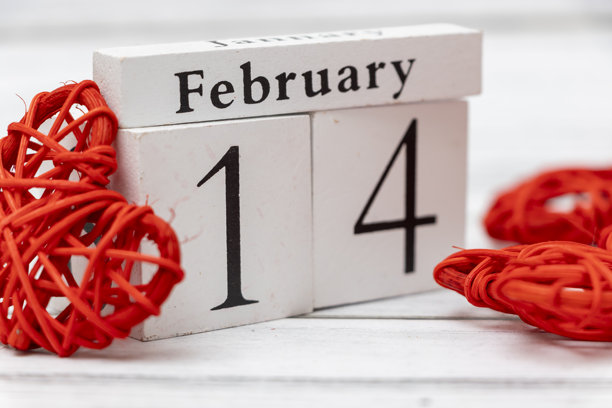 这张照片展示了一个木质日历，显示日期为2月14日，象征着情人节。装饰性的红心增强了浪漫主题，唤起了爱的感觉。图片下载