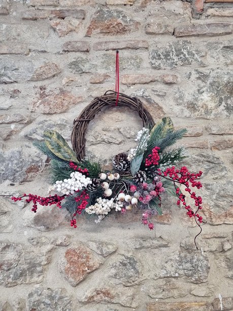 乡村石头墙上的自然葡萄藤圣诞花环，饰有松果和霜冻浆果图片下载