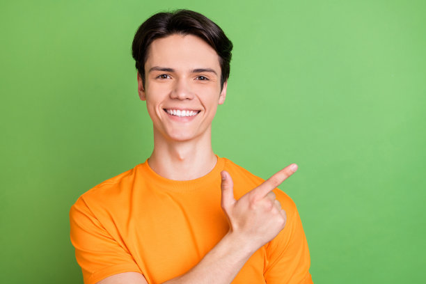 照片：一位面带微笑、魅力十足的男士，伸出手指指向绿色背景上的空白空间，仿佛在挑选特卖新闻，表情积极愉悦。图片下载