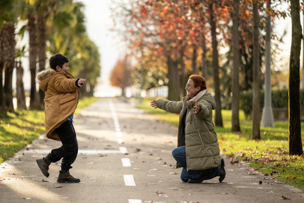 一个孩子跑进城市公园，跳进妈妈的怀抱并拥抱她。系列照片的一部分图片下载