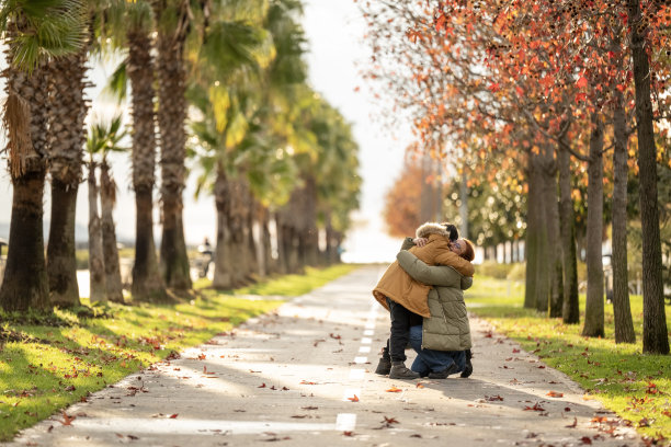一个孩子跑进城市公园，跳进妈妈的怀抱并拥抱她。系列照片的一部分图片下载