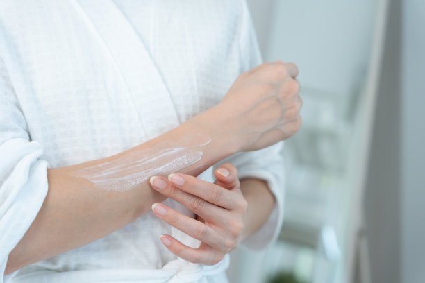 美丽的亚洲女子微笑使用面霜，拥有健康肌肤。健康的女子涂抹身体乳。宣传皮肤霜、抗皱、婴儿肌、美白、保湿、收缩毛孔精华。图片下载