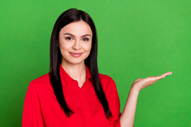 身穿红衬衫的漂亮棕发女商人在绿色背景前手持空白空间，供素材使用图片下载