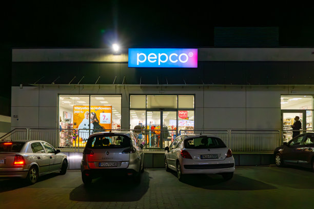 夜间佩普科商店入口照片，有发光的招牌和前面停放的几辆汽车图片下载