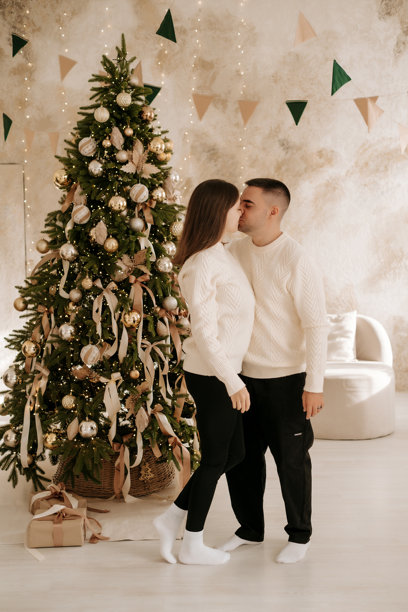 新年，一对年轻夫妇，一男一女，站在圣诞树旁，互相祝贺节日，等待节日到来，一对相爱夫妇的家庭照片图片下载