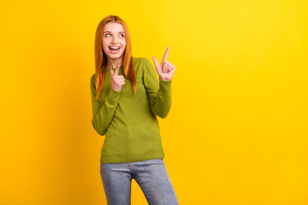 身穿绿色毛衣的千禧一代红发酷女孩，看向画面空白处，背景为黄色图片下载