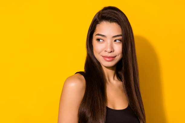 照片：一位梦想着、积极乐观、快乐的年轻女子，眼神空洞，在黄色背景上想象着，孤立图片下载