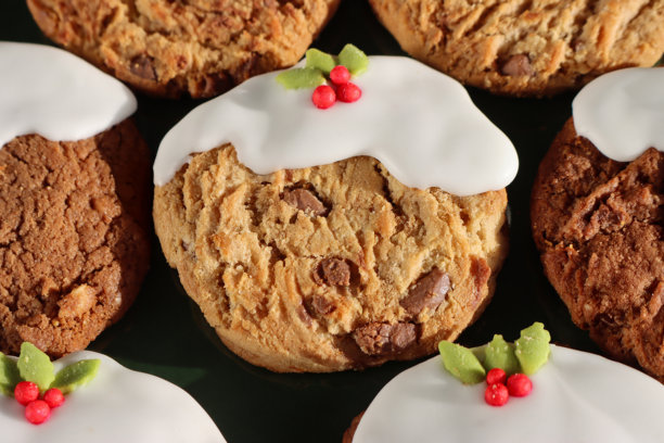 全景图，绿色盘子里的圣诞布丁设计巧克力碎酥饼，无花果布丁风格的白皇家糖霜装饰节日三倍巧克力和牛奶巧克力碎饼干，冬青叶和浆果，俯视角度图片下载