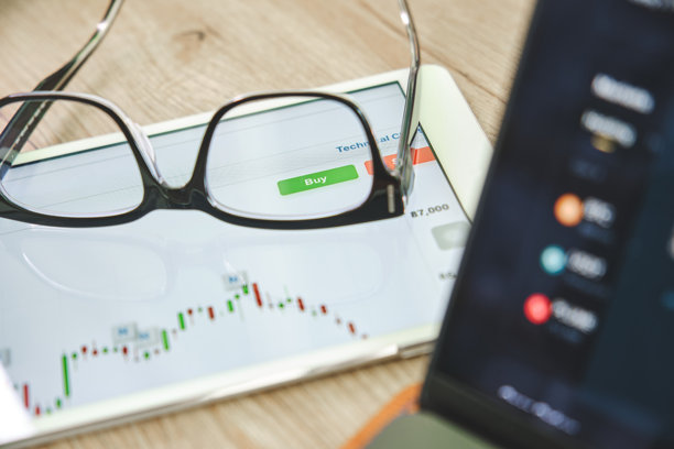 平板电脑上放着一副眼镜，屏幕显示着股票市场图表和一个购买按钮图片下载