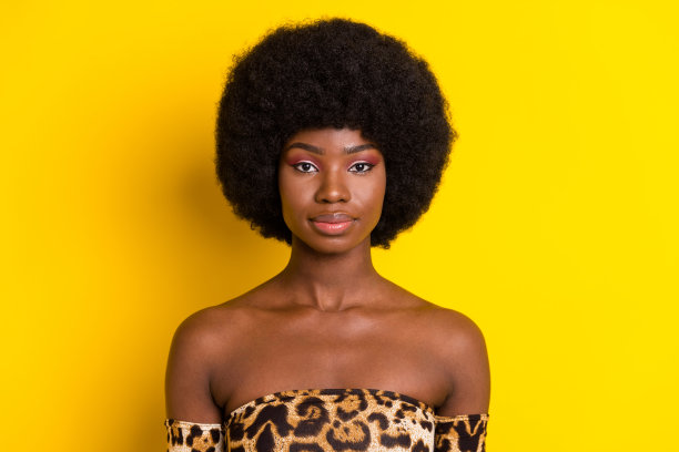 照片肖像，卷发女性，身穿豹纹印花上衣，在明亮的黄色背景下拍摄图片下载