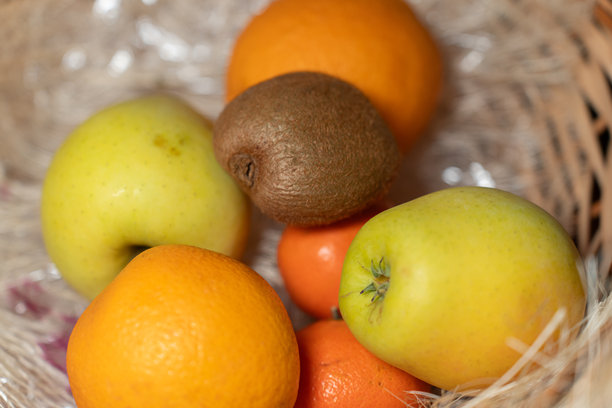 一个柳条篮里摆放着色彩鲜艳的新鲜水果，包括苹果、橙子、橘子和猕猴桃。这张图片传达了自然清新、健康饮食和有机生活方式的主题。图片下载