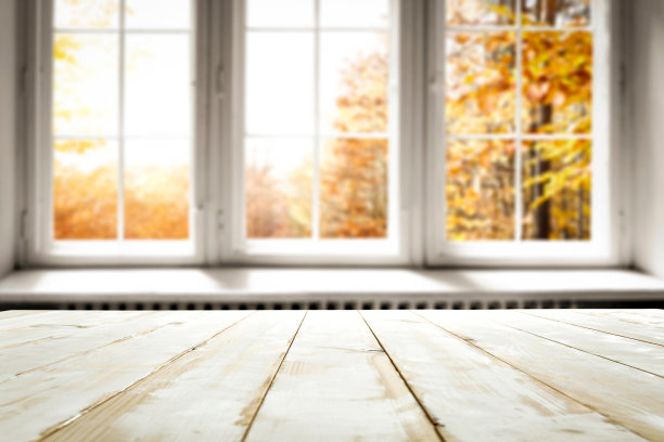 宁静的秋季窗户照片，可以看到五彩缤纷的秋叶，以及展示室内季节之美和宁静的木桌表面。图片下载