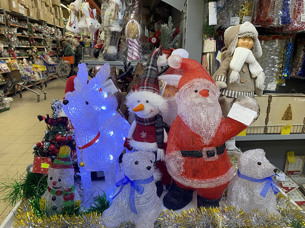 一家商店里节日气氛浓厚的展示架。圣诞老人玩偶、驯鹿、雪人、北极熊。闪亮的饰带、闪光彩条。新年装饰、圣诞树枝。超市促销、购物照片图片下载