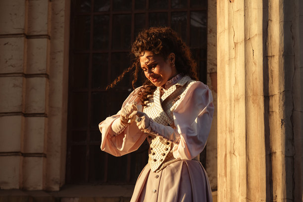 一位身着复古连衣裙的女子在古老大教堂的柱子旁阅读信件。图片下载