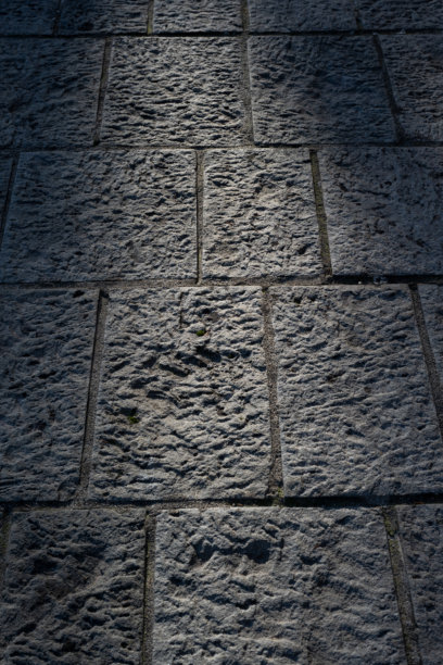 一张高分辨率的特写照片，展示了具有深邃纹理和不规则浮雕的饱经风霜的石板。光影的交错突显了材料的天然凹槽和古朴质感。图片下载