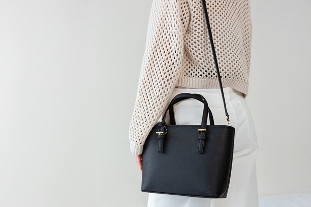 模特的手中拿着一个黑色的小款女士手提包。一款现代时尚手提包的特写照片。日常穿搭的时尚配饰图片下载