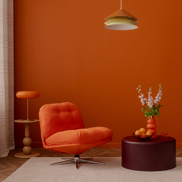 复古风格的室内设计，配有橙色休闲椅、彩色吊灯和雕塑花瓶。温暖的橙色墙壁和俏皮的造型营造出愉悦的氛围。图片下载