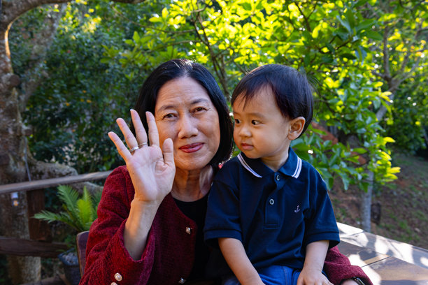 一位年长的亚洲女性和一名亚洲婴儿正在微笑着看向镜头，进行视频通话。温馨的亲子时刻，充满爱意。素材照片图片下载