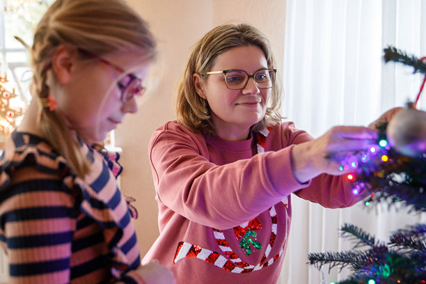 小女孩和妈妈在家用复古装饰品和玩具装饰传统的圣诞树图片下载