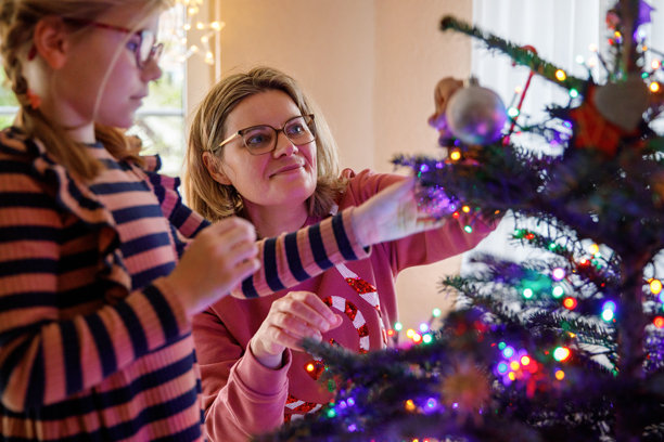 小女孩和妈妈在家用复古装饰品和玩具装饰传统的圣诞树图片下载