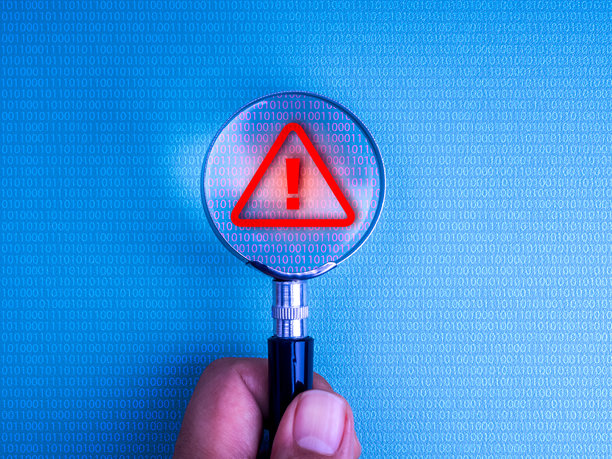 手持放大镜扫描电脑屏幕上的二进制代码，发现红色警告符号。网络安全警报、诈骗检测、数据泄露、在线威胁监控和数字风险的概念。图片下载