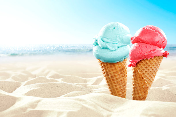 阳光明媚的夏日，在沙滩上，背景是美丽的大海，美味的粉色和蓝色冰淇淋蛋筒照片。图片下载