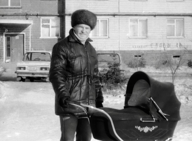 一位快乐的年轻父亲推着婴儿车带儿子散步的复古肖像。摄于 1988 年的复古照片。图片下载