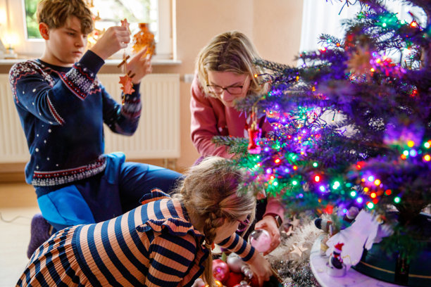 小女孩、少年和母亲在家用复古装饰品和玩具装饰传统的圣诞树图片下载