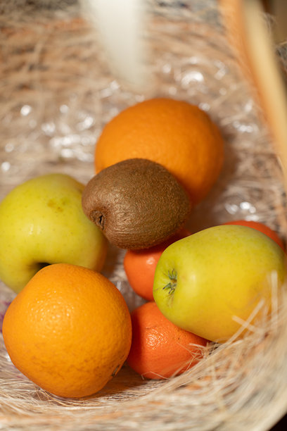 一个柳条篮子里盛放着各种鲜艳的新鲜水果，包括苹果、橙子、橘子和猕猴桃。这张图片传达了自然清新、健康饮食和有机生活方式的主题。图片下载