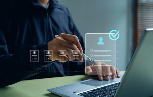 一位商务专业人士正在笔记本电脑上审阅数字简历，旁边有虚拟清单图标，这说明了在线招聘、人力资源技术、候选人评估和现代招聘工作流程。图片下载