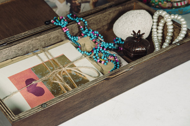 木制纪念盒，里面放着旧明信片和信件，色彩鲜艳的手工种子珠项链，白纸板背景图片下载