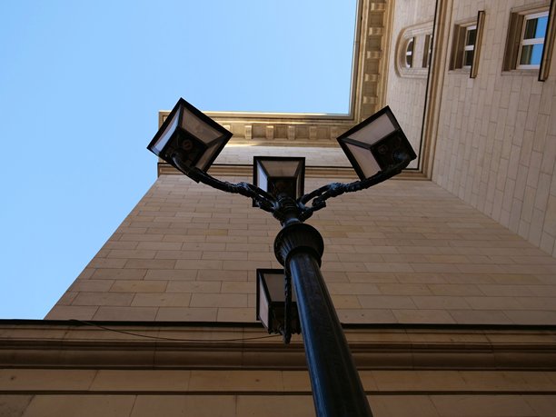 复古风格的黑色三灯柱路灯，背景是晴朗的蓝天。图片下载