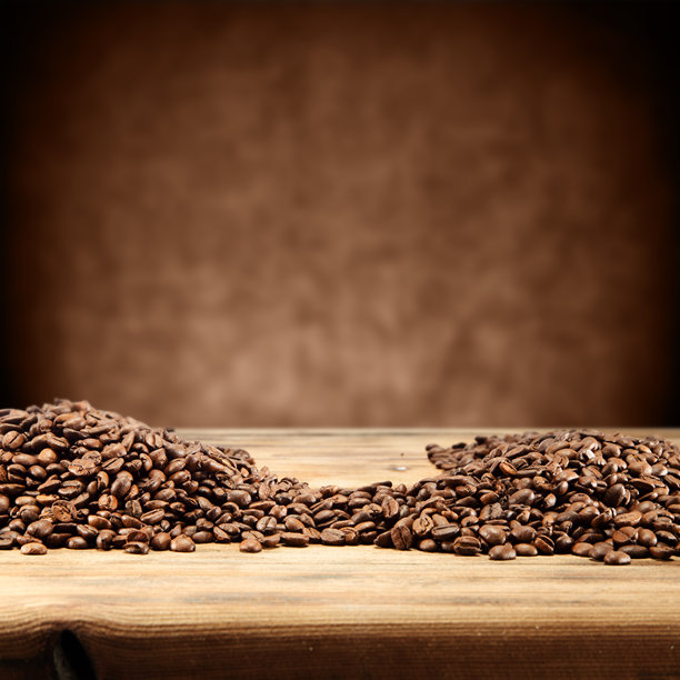 在木质表面堆放的烘焙咖啡豆，营造出温暖诱人的背景照片，适合咖啡馆和咖啡店的宣传材料图片下载