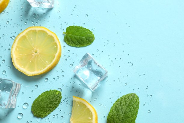 俯视拍摄的薄荷叶、柠檬片、冰块和水滴在粉蓝色背景上的照片图片下载