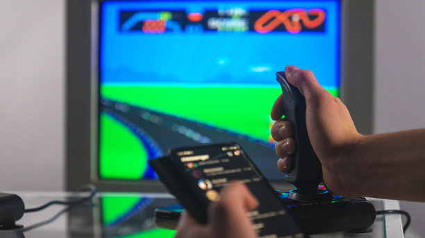 在CRT电视上玩老派的8位游戏，同时用现代手机发短信。图片下载