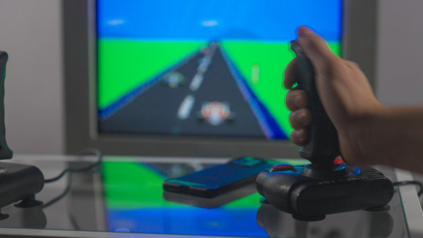 在CRT电视上玩老式8位游戏，桌子上放着现代手机。图片下载