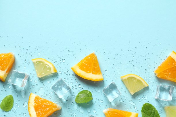 俯视视角拍摄的薄荷叶、橙子片、柠檬片、冰块和水滴在粉蓝色背景上的照片图片下载