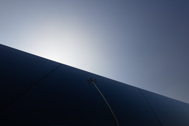 抽象的城市墙壁，配以逆光天空和孤单的路灯，戏剧性的极简主义照片图片下载