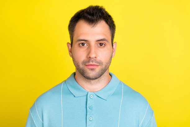 照片：英俊的棕发男子穿着蓝色马球衫，在黄色背景下拍摄图片下载