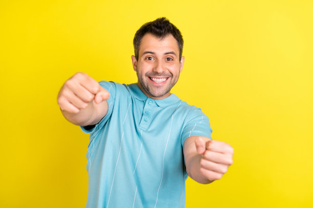 照片：穿着蓝色T恤的时尚棕发男子，在黄色背景下开车图片下载