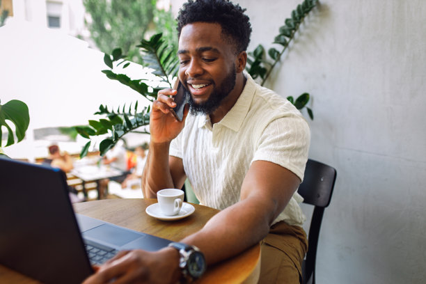 男人微笑着坐在咖啡馆里，正在打电话。图片下载