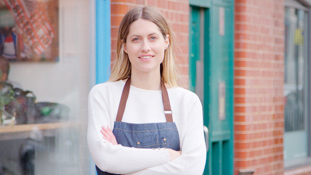 当地商业街上，一位面带微笑的女小企业主站在店外拍摄肖像照图片下载