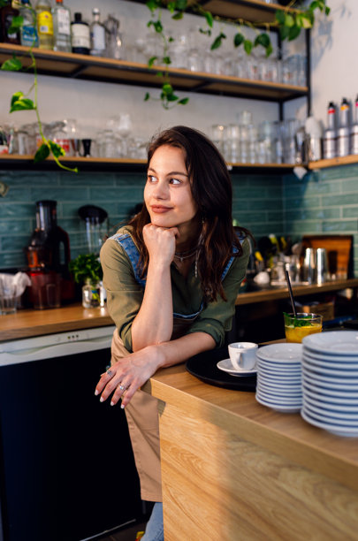 女咖啡师站在咖啡店柜台后面肖像照。图片下载