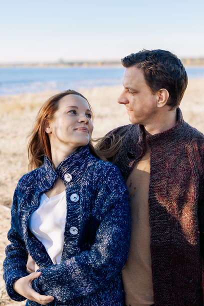 恩爱的夫妇在阳光明媚的秋日沿着大海在海滩上散步。周末和生活方式的概念。竖式照片图片下载