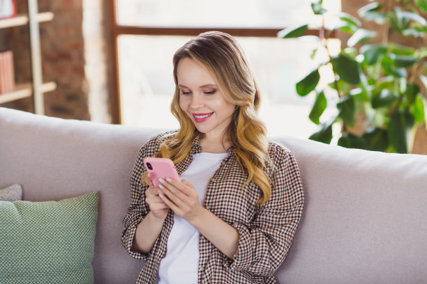 穿着格子衬衫的可爱年轻女子在室内房子家里房间里看现代小工具的照片图片下载